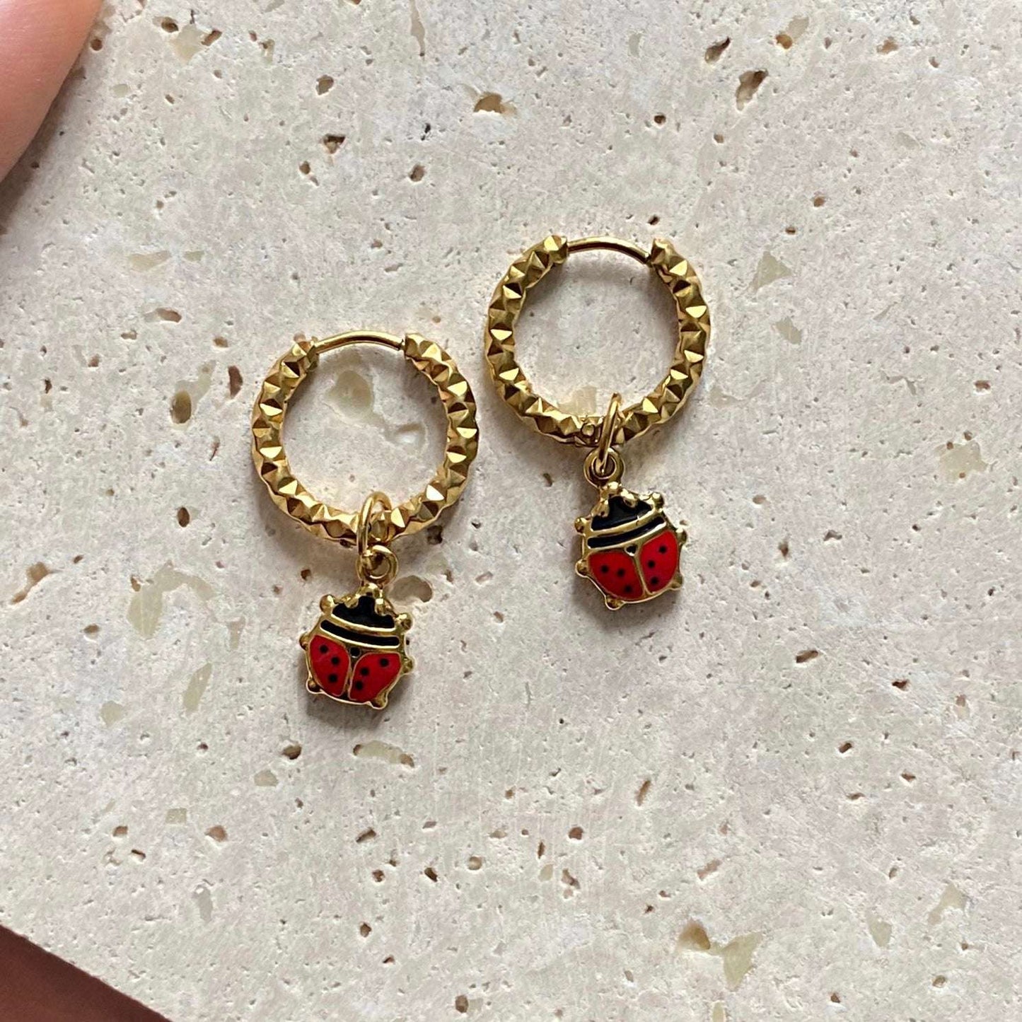 Boucles d’oreilles créoles en acier inoxydable dorées avec deux pendentifs coccinelle .