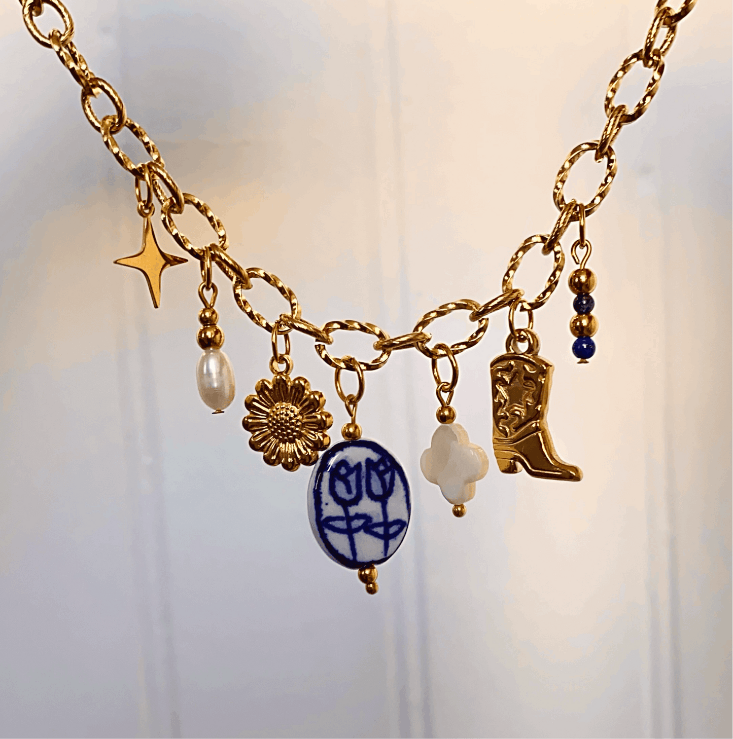 Collier en acier inoxydable doré avec 7 pendentifs de couleur bleu, blanc et doré.