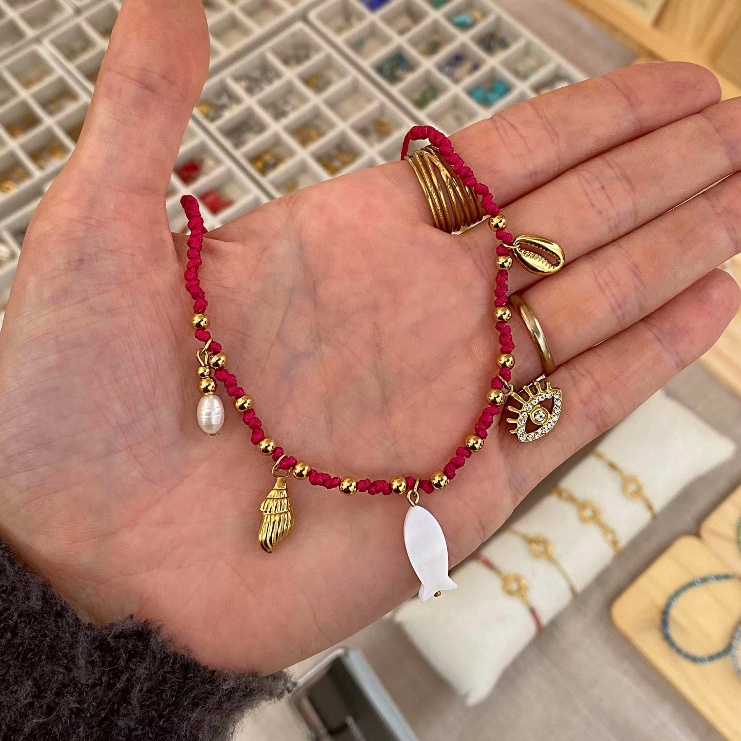 Collier en fil nylon rose et perles dorées composé de 5 pendentifs dorés et blancs.