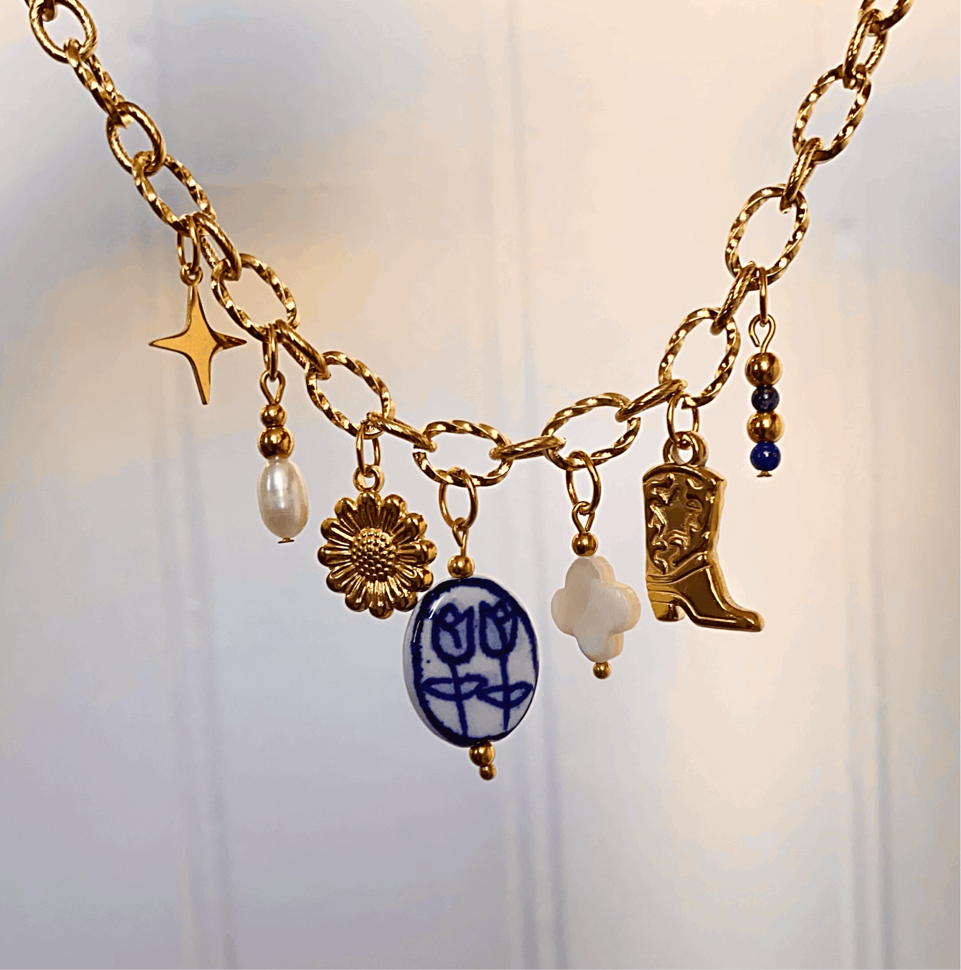 Collier en acier inoxydable doré avec 7 pendentifs de couleur bleu, blanc et doré.
